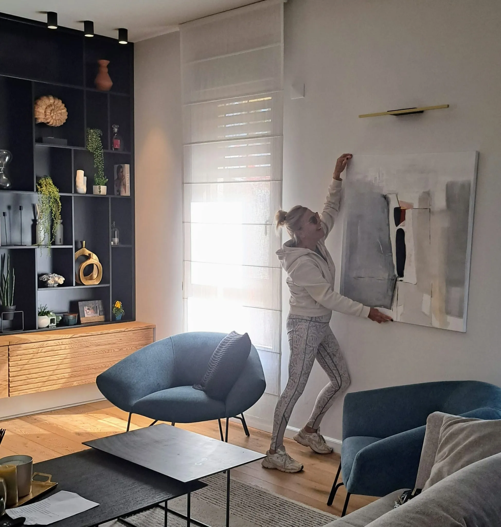 Paula Harmsen hanging a finished painting on a client's wall